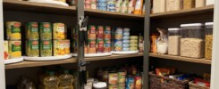 Organized pantry shelves with canned foods, dry grains, cooking oil and a manual can opener.