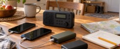 AI-generated illustration of a battery radio, two phones, power banks, charging cables, notebook and map on a household table.